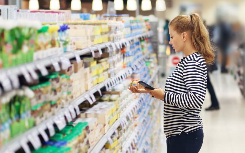 Femme lisant une étiquette alimentaire au supermarché